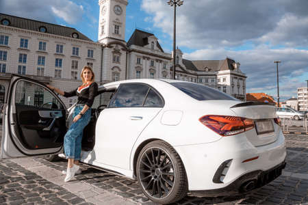 Young attractive model is sitting near the car. Girl sitting near a car. sensual girl enjoying sunset. Traveling.の写真素材
