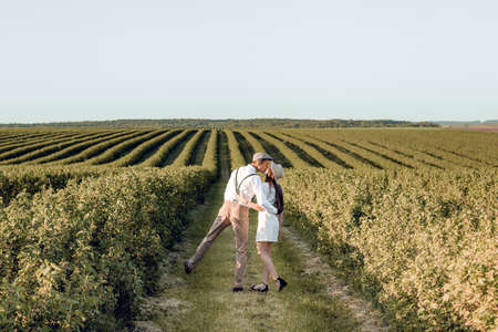Couple holding hands and walking on green meadow. Romantic couple having fun in the field. A beautiful couple in the style. Love Story photohoot.の写真素材
