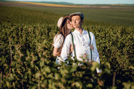 Young beautiful couple in love sitting and hugging in a green field with bushes. Walking in the green field on a sunny summer day.の写真素材