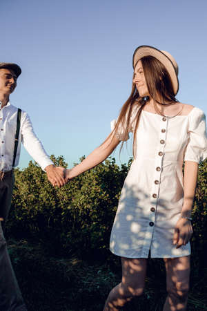 Young beautiful couple in love sitting and hugging in a green field with bushes. Walking in the green field on a sunny summer day.の写真素材