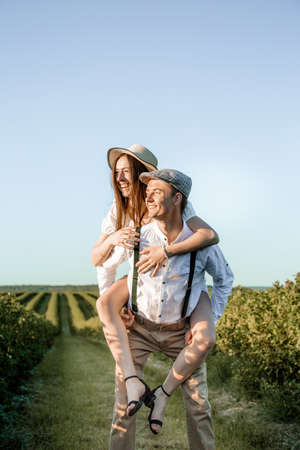 Young beautiful couple in love sitting and hugging in a green field with bushes. Walking in the green field on a sunny summer day.の写真素材