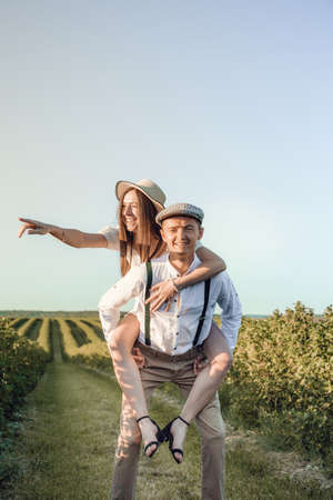 Young beautiful couple in love sitting and hugging in a green field with bushes. Walking in the green field on a sunny summer day.の写真素材