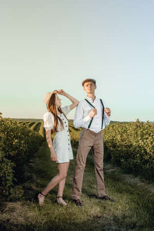 Young beautiful couple in love sitting and hugging in a green field with bushes. Walking in the green field on a sunny summer day.の写真素材