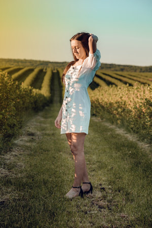 Pretty girl walks in a field with field flowers and smiles sincerely. Beautiful girl enjoying a field, relaxing outdoors, having fun, harmony concept. Traveling.の写真素材