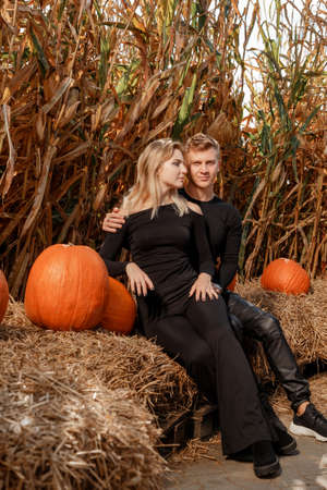 Happy family sitting on hay bales and holding pumpkins at outdoor market. Autumn time.の写真素材