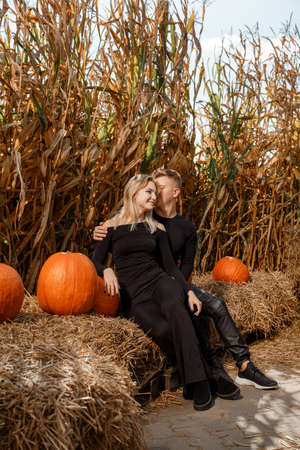 Happy family sitting on hay bales and holding pumpkins at outdoor market. Autumn time.の写真素材