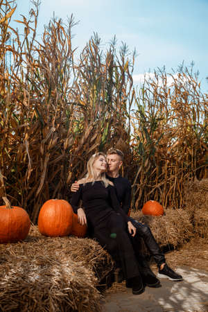 Happy family sitting on hay bales and holding pumpkins at outdoor market. Autumn time.の写真素材