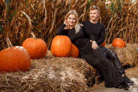 Happy family sitting on hay bales and holding pumpkins at outdoor market. Autumn time.の写真素材