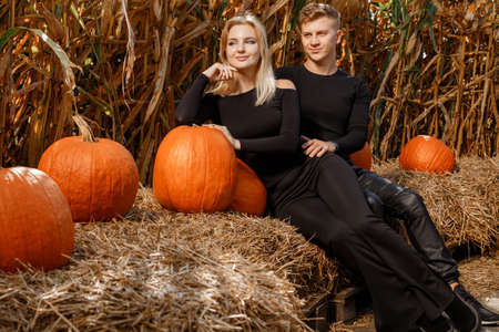 Happy family sitting on hay bales and holding pumpkins at outdoor market. Autumn time.の写真素材