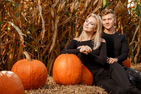 Happy family sitting on hay bales and holding pumpkins at outdoor market. Autumn time.の写真素材