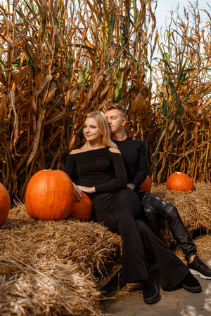 Happy family sitting on hay bales and holding pumpkins at outdoor market. Autumn time.の写真素材