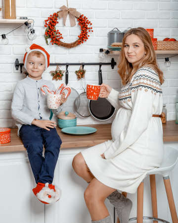 Pregnant mother and her son enjoying in kitchen and christmast time. Pregnant woman with son on New Year's holidays.の写真素材