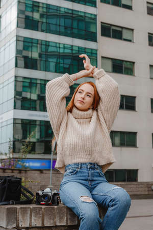 Red hair woman on street ladder. Red haired woman in stylish outfit. Fashion style girl with long...