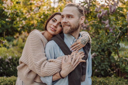 Smiling tattooed girl hugging her boyfriend in a park. Pretty redhead woman with tattoos and man on...