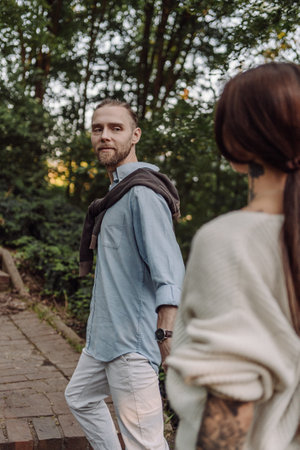 Outdoor shot of young couple in love walking on pathway through grass field. Young couple strolling...