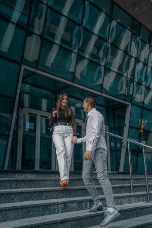 Young couple in love sitting on stairs, talking. Smiling beautiful woman and her handsome boyfriend....