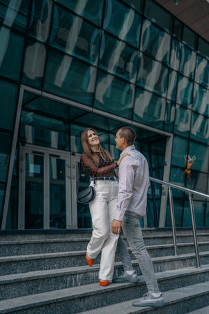 Young couple in love sitting on stairs, talking. Smiling beautiful woman and her handsome boyfriend....