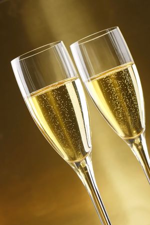 Glasses of champagne with gold background with walnuts, candels and dryed raisinsの写真素材