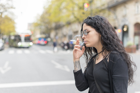 Smoking beautiful woman in the street.の写真素材