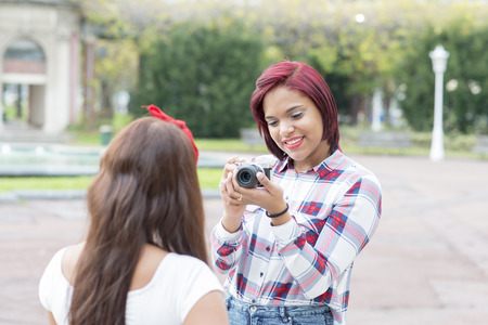 Smile woman taking pictures of her friends in the park.の写真素材