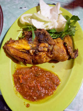 Brownish-yellow chicken, being put on a long plate, with two kinds of vegetables, such as cabbage and kumangi, then added with a spicy chili sauceの写真素材