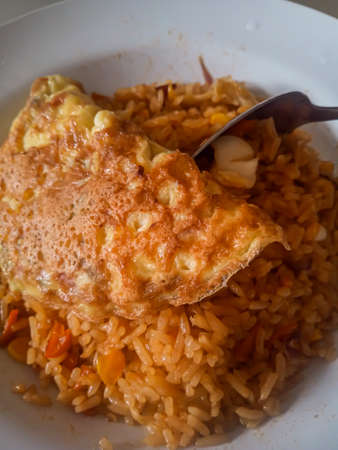 Reddish fried rice that has just been removed from the stove and then served on a plate to eat before it coolsの写真素材