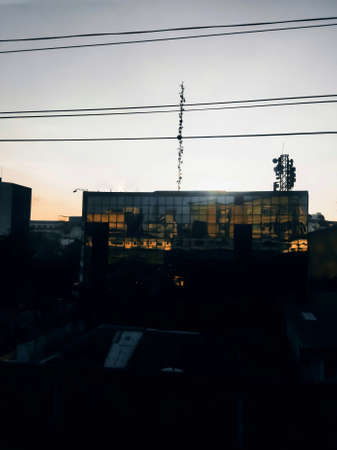 The sunsets from behind a tall building, the horizon is orange and looks beautiful behind the...