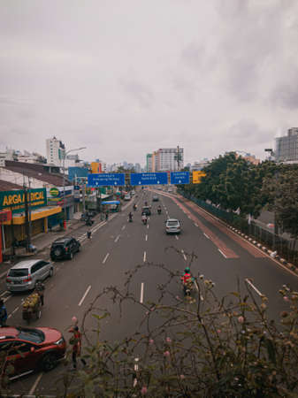 A long and straight highway in Jakarta Indonesia as seen from above the bridge, on the right side there are shady trees that grow well.のeditorial素材