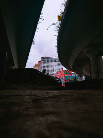 Jakarta Pusat, Indonesia - 14 February 2021: Many vehicles pass on the highway, which is located under two concrete bridges with a backdrop of colorful buildings.のeditorial素材