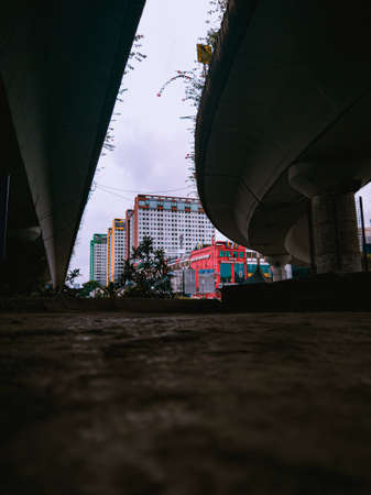 Jakarta Pusat, Indonesia - 14 February 2021: Many vehicles pass on the highway, which is located under two concrete bridges with a backdrop of colorful buildings.のeditorial素材