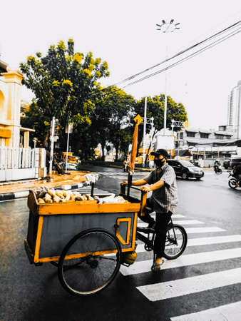Jakarta Pusat, Indonesia, February 16th, 2021: Male greengrocer who drives his vegetable cart down the street, and is looking for the best place to sell so that it sells wellのeditorial素材