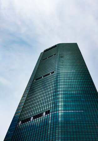 Central Jakarta, Indonesia - March 12th, 2021: A tall green BCA building under a clear sky with fluffy clouds.のeditorial素材