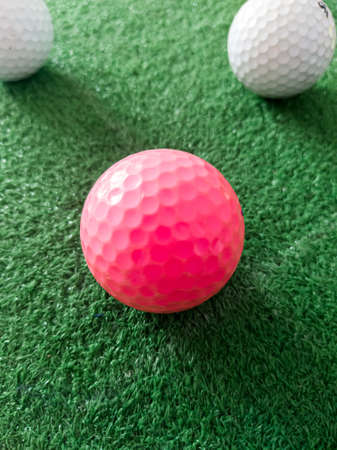 pink and white golf ball on grass.の写真素材