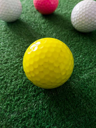 yellow and white golf ball on grass.の写真素材