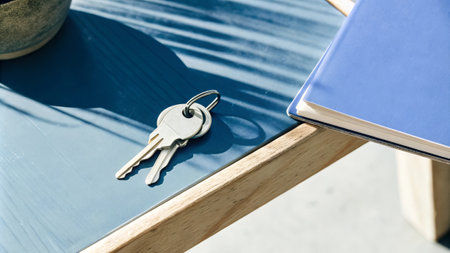 Minimalist workspace featuring keys, notebook, and natural light.の素材
