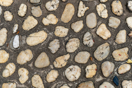 Smooth stones embedded in concrete pavement outdoors.