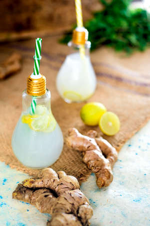 Ginger lemonade juice is served in bulb glasses with ginger and mint leaves surrounded by it. It is placed on the brown sack. It is a refreshing drink for summers.の写真素材