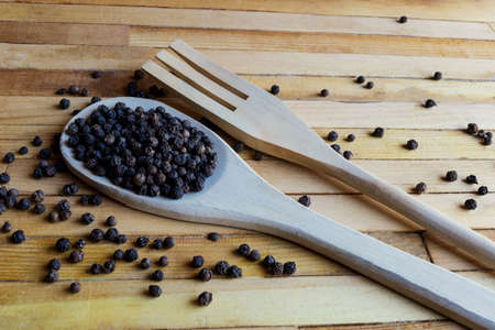 wooden Kitchen spatula full of peppercorns and kitchen fork on wooden background.の写真素材