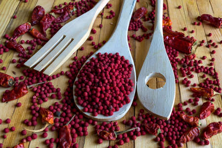 wooden spoon full of dry red peppercorn on wooden background.の写真素材