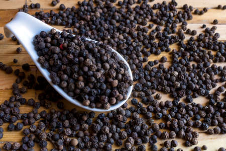 Dry Black pepper corns  in white porcelain spoon.の写真素材