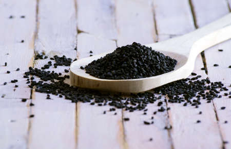 Close-up of Kitchen spatula full of Organic black seeds on white rustic background.の写真素材