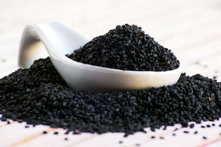 close -up of a pile of black seeds in porcelain white spoon. Selective focus.の写真素材