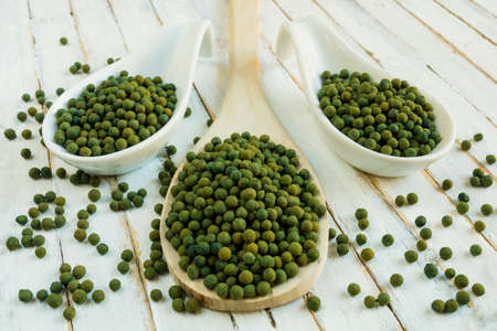 three spoons full of green peppercorn on rustic white background.の写真素材