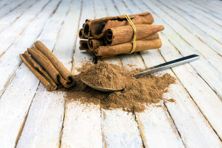a spoon full of Cinnamon powder beside Cinnamon sticks on rustic wooden background.の写真素材