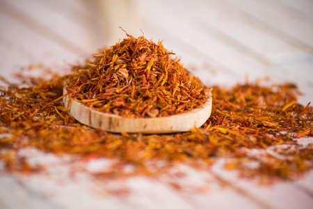 dried Safflower in wood spoon on rustic white background.の写真素材