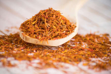 close-up of Safflower dried in wood spoon on rustic white backgroundの写真素材