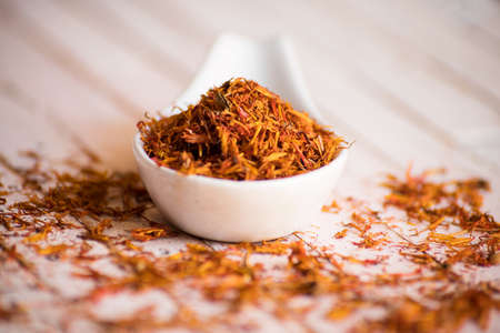 white porcelain spoon full of dried saffron on rustic background, soft focus.の写真素材