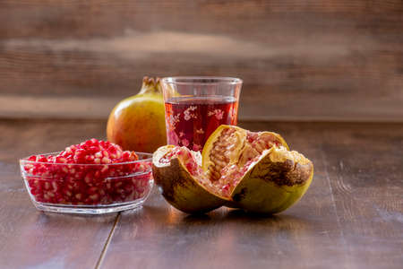 Pomegranate juice, pomegranate juice and pomegranate seeds in glass bowl on wooden backgroundの写真素材