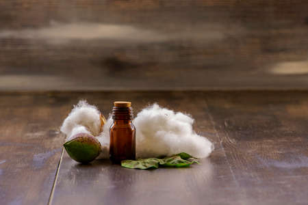 White cottons, cocoons and cottonseed oil in a bottle on a wooden floor.の写真素材