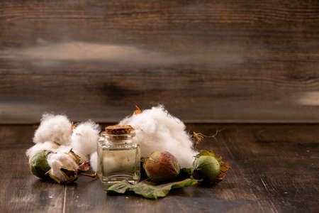 White cottons, cocoons and cottonseed oil in a bottle on a wooden floor.